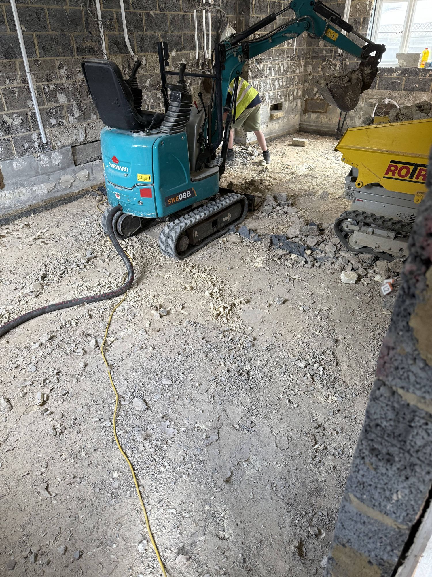 Floor slab broken out — a Sunward SWE08B mini excavator brought indoors to start from scratch