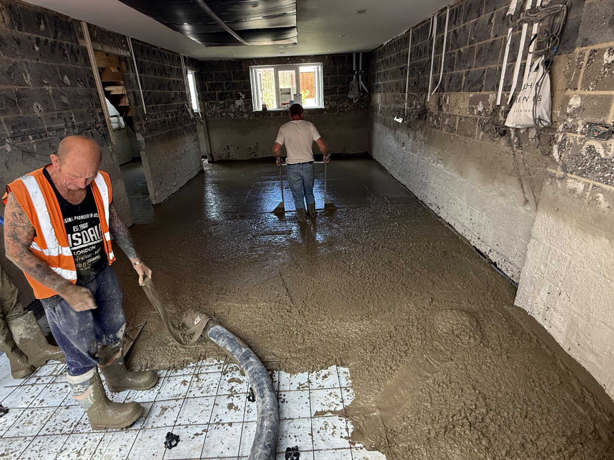 Concrete slab being poured and hand levelled, ready to be machine floated