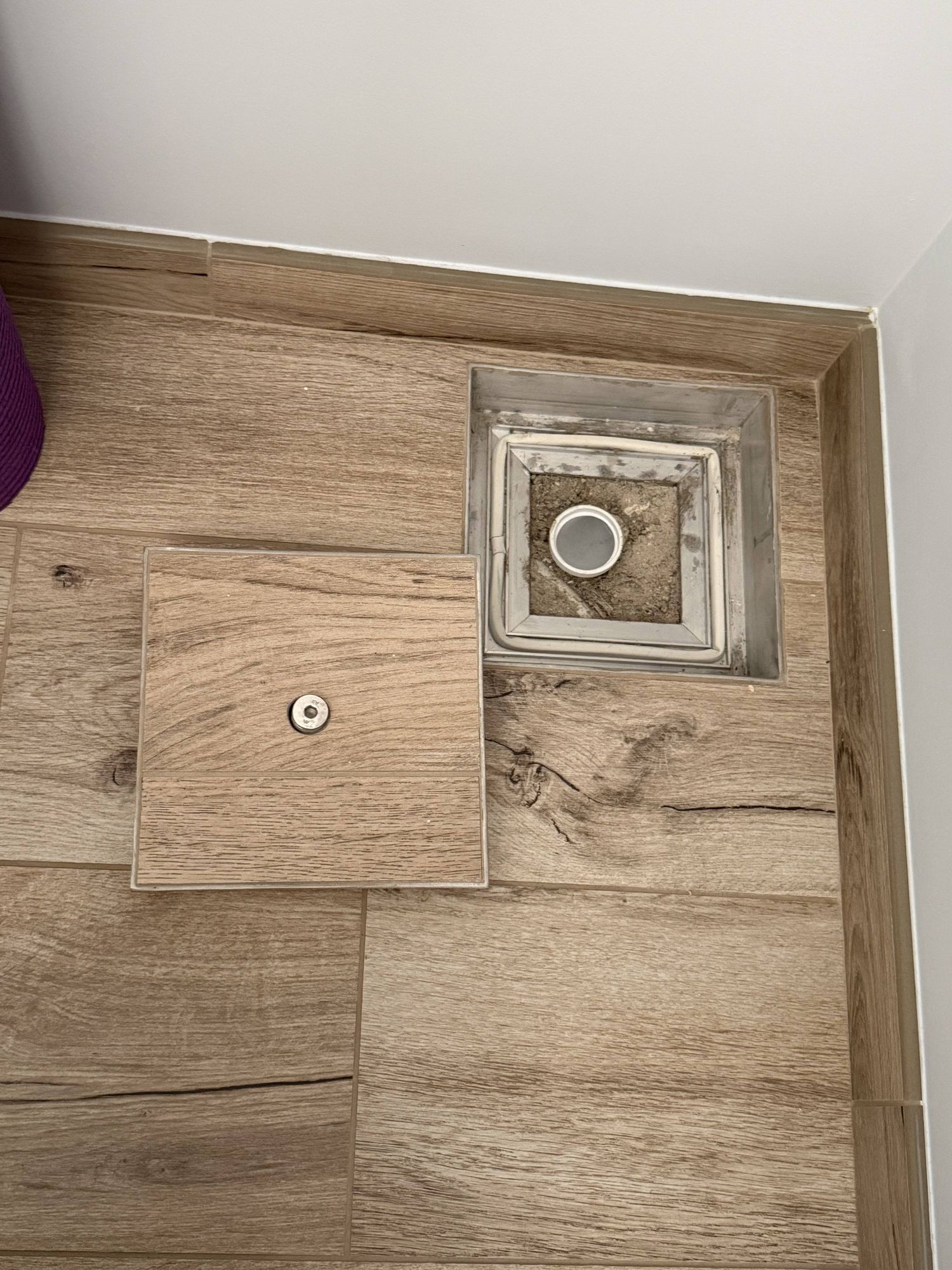 Floor-level concealed service hatch — flush-fitted with matching tiles, open to show access to the sump drain system