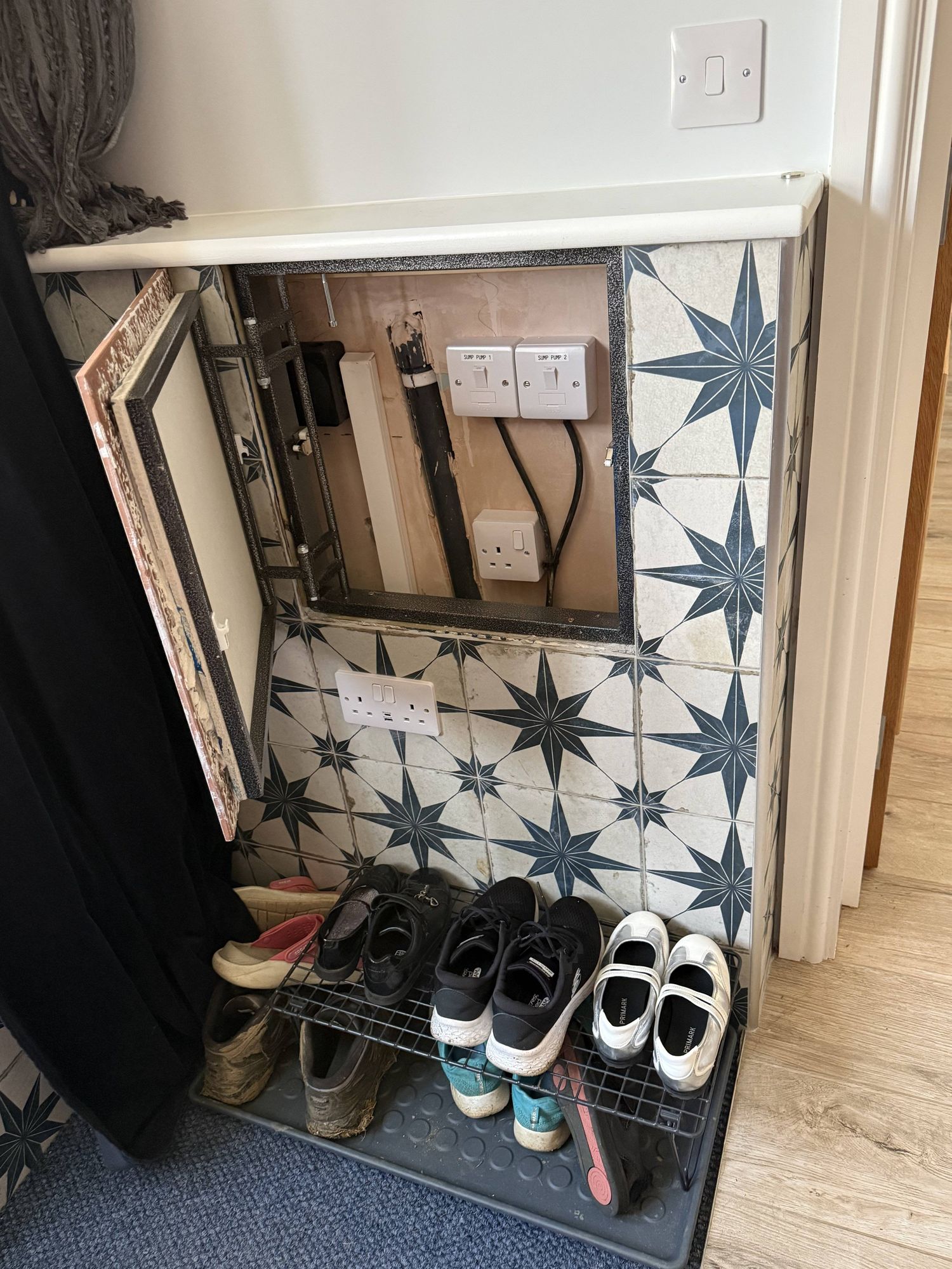 Sump pump service cabinet — electrical controls for pump one and two concealed behind a tile-matched hatch